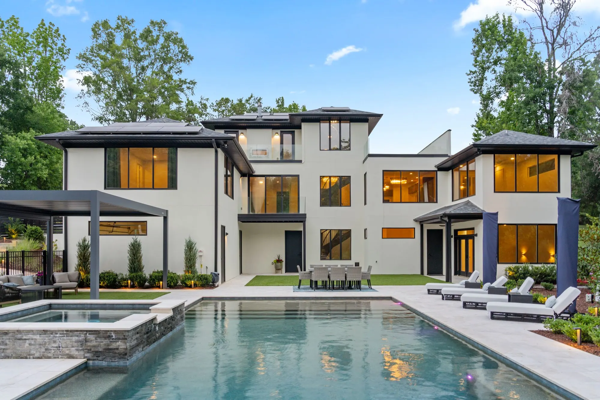 Rear of the residence across the 20 x 40 heated pool and raised spa, lights on at dusk
