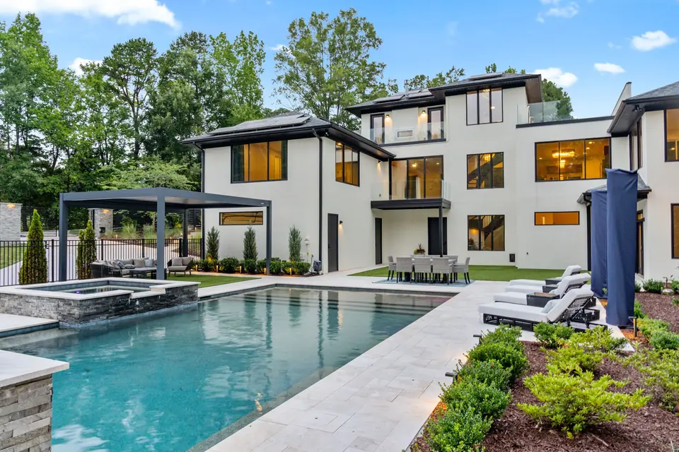 Heated pool, raised spa and marble decking with the house lit behind