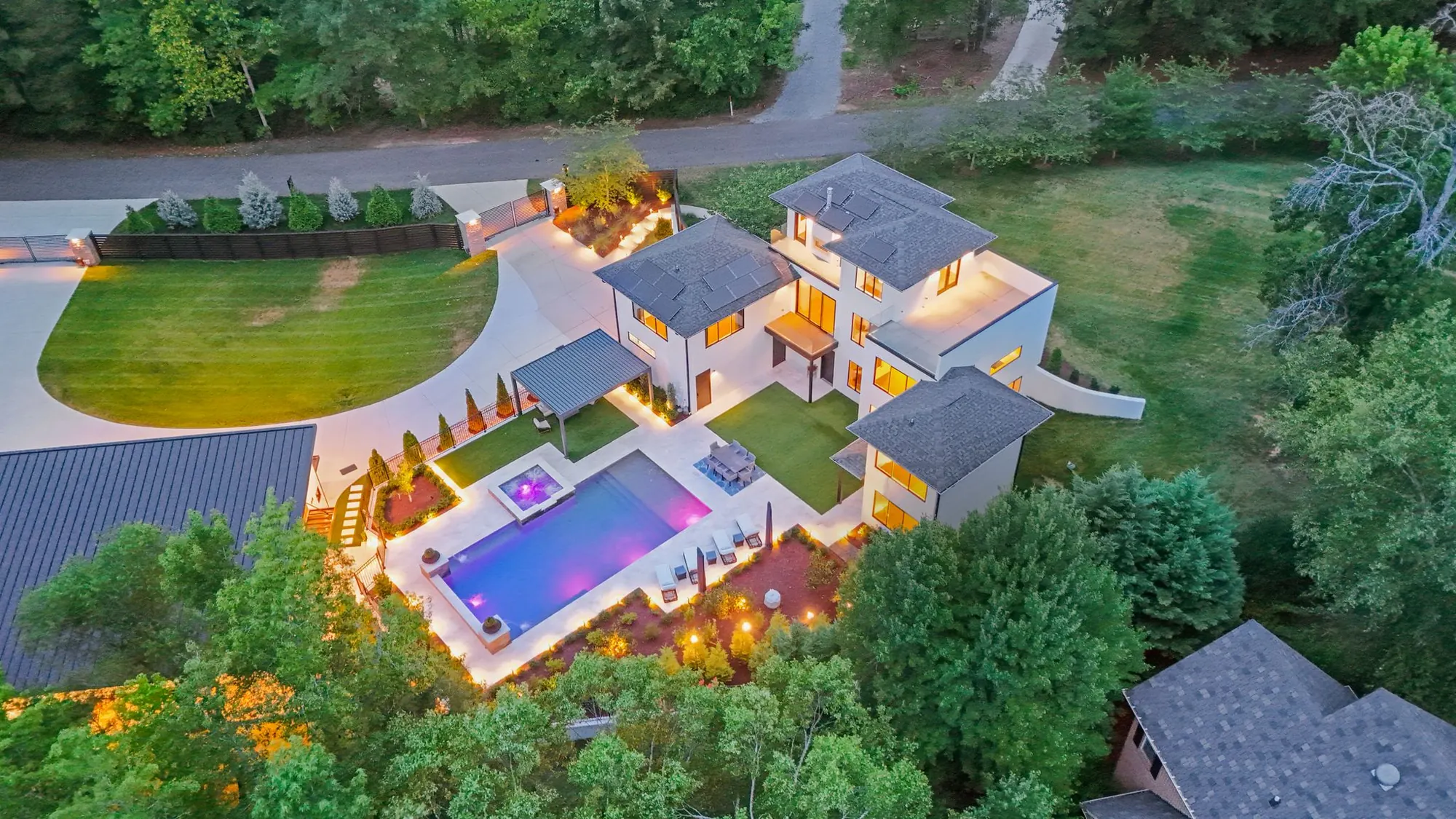 Aerial view at twilight showing the lit pool, house and circular drive on 1.58 acres